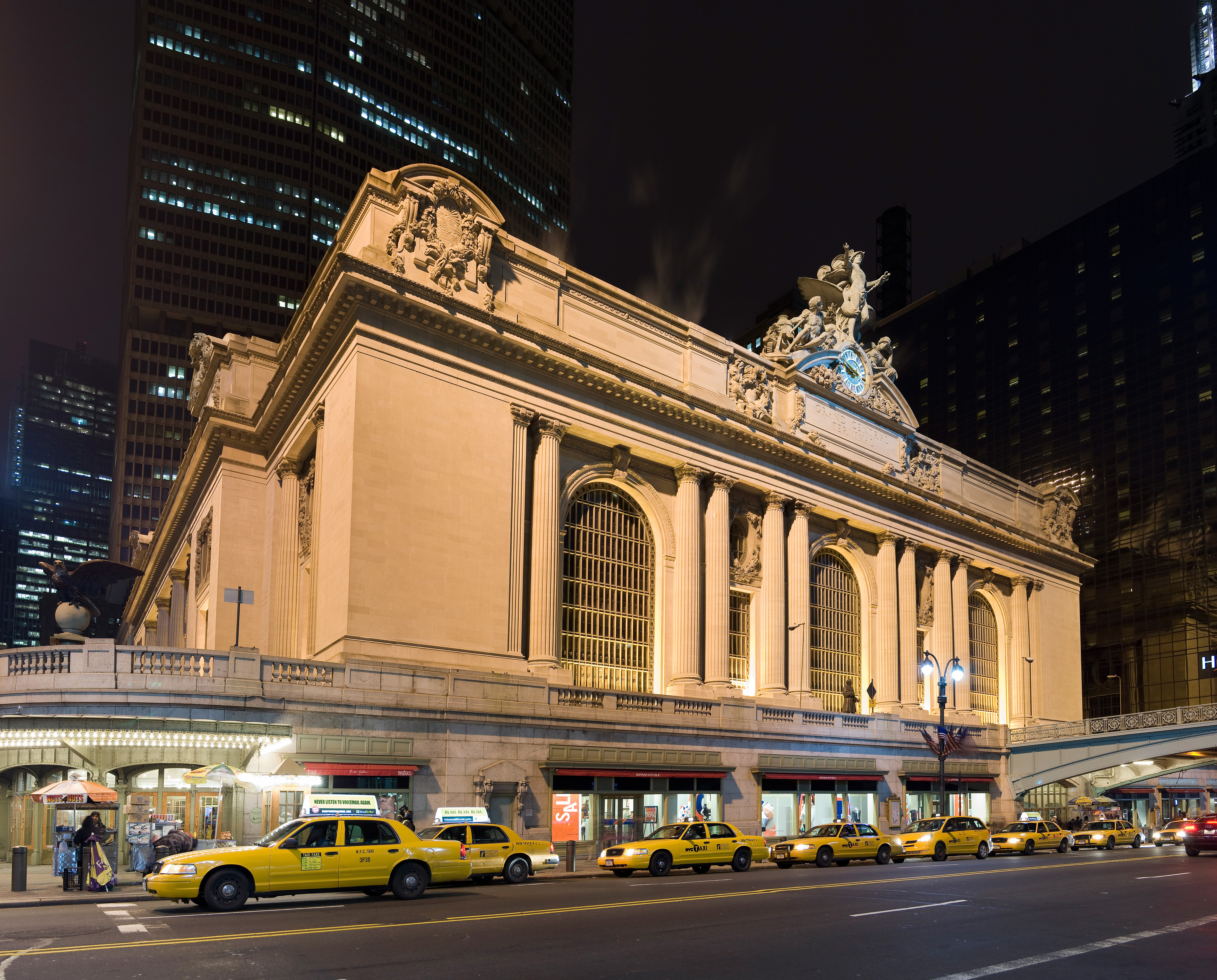 Grand Central Terminal facade lit up at night with taxis outside